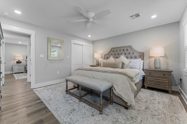 bedroom with wood finished floors, a closet, baseboards, visible vents, and recessed lighting