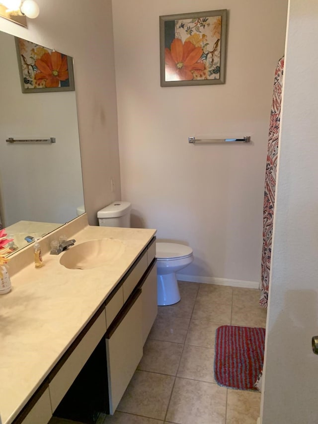bathroom featuring baseboards, vanity, tile patterned flooring, and toilet