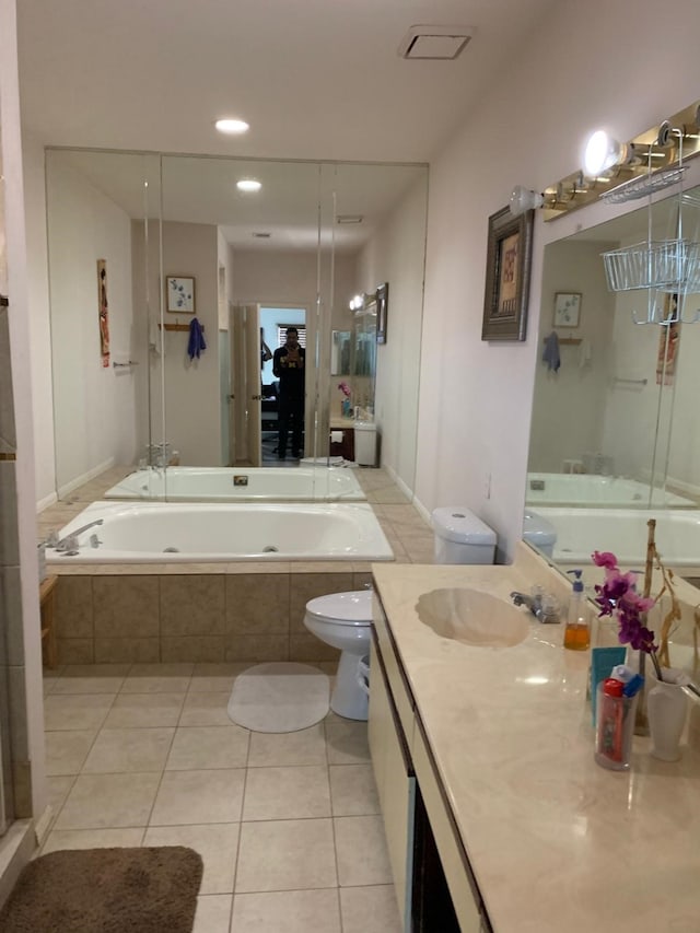 bathroom featuring vanity, tiled tub, toilet, tile patterned flooring, and recessed lighting