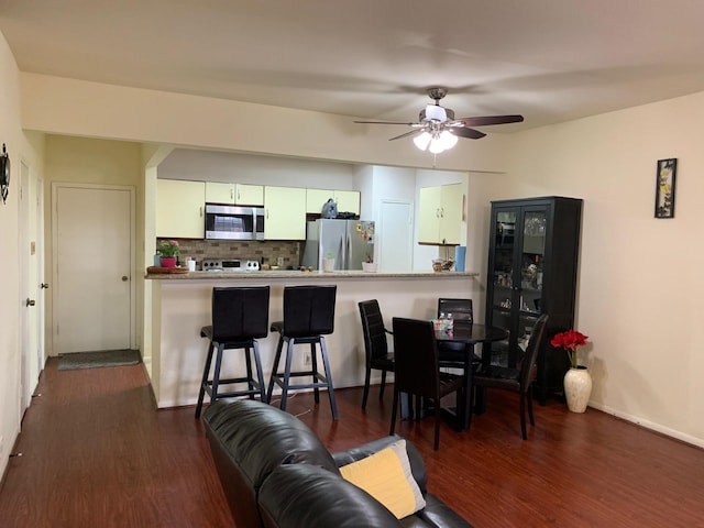 kitchen featuring a ceiling fan, white cabinets, appliances with stainless steel finishes, backsplash, and dark wood-style flooring