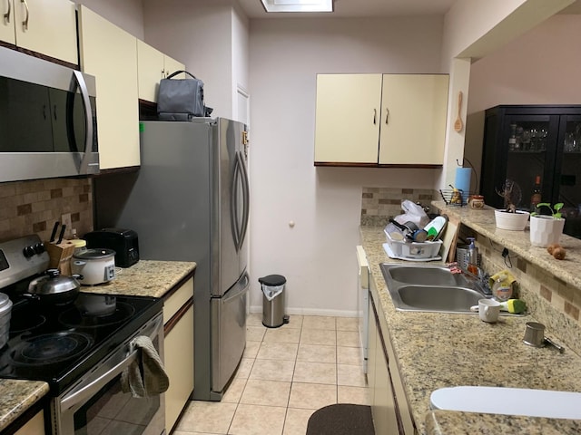 kitchen featuring a sink, light tile patterned floors, stainless steel appliances, light countertops, and backsplash