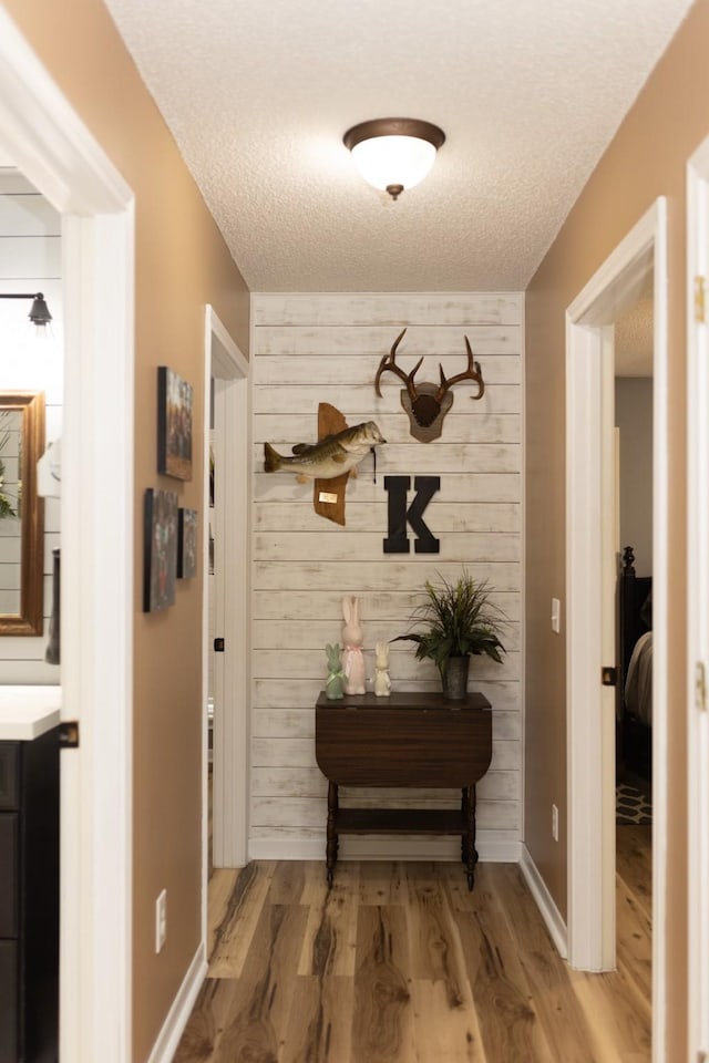 1867 Fm 2423, Grapeland, TX 75844 - corridor with a textured ceiling, baseboards, an accent wall, wood finished floors, and wooden walls