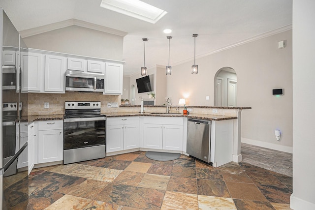2884 Shallow Brook Ln, Dickinson, TX 77539 - kitchen featuring stainless steel appliances, arched walkways, stone tile floors, a peninsula, and decorative backsplash