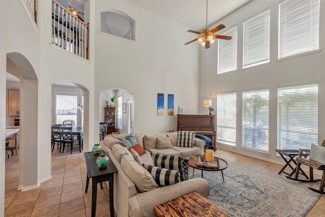 6919 S Gold River Cir, Missouri City, TX 77459 - living area with a ceiling fan, light tile patterned floors, arched walkways, a towering ceiling, and baseboards