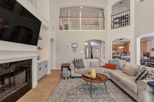 6919 S Gold River Cir, Missouri City, TX 77459 - living room featuring a fireplace, arched walkways, a towering ceiling, and light tile patterned floors