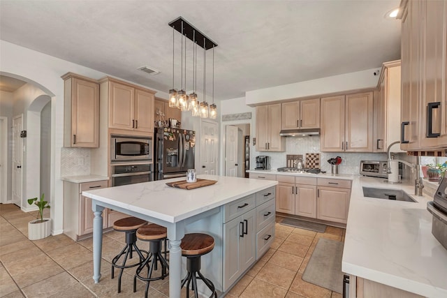 6919 S Gold River Cir, Missouri City, TX 77459 - kitchen with a kitchen bar, appliances with stainless steel finishes, and light brown cabinetry