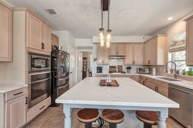 6919 S Gold River Cir, Missouri City, TX 77459 - kitchen with under cabinet range hood, visible vents, light brown cabinets, a sink, and appliances with stainless steel finishes