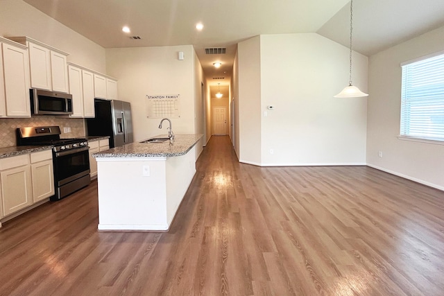 18871 Cedar Birch Ln, Magnolia, TX 77355 - kitchen featuring stainless steel appliances, a sink, dark stone counters, a center island with sink, and light wood-type flooring