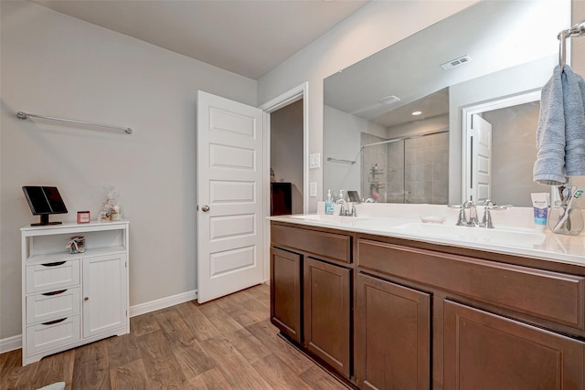 full bathroom featuring a stall shower, a sink, wood finished floors, and visible vents