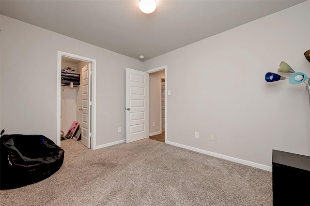 carpeted bedroom with a spacious closet and baseboards