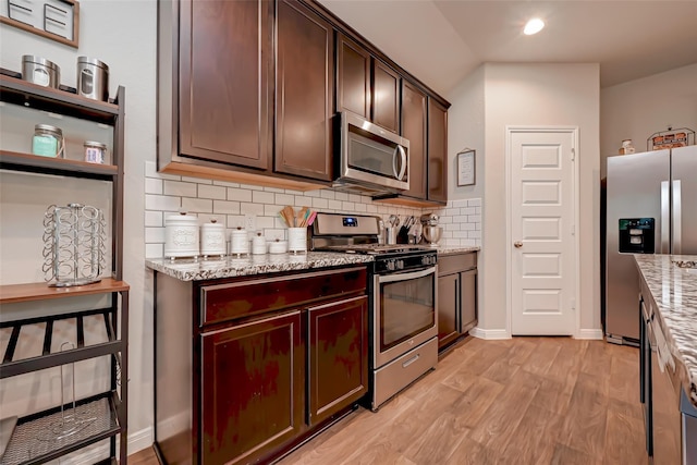 kitchen with appliances with stainless steel finishes, light stone counters, decorative backsplash, and light wood-style flooring