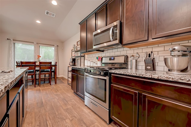 kitchen with light stone countertops, tasteful backsplash, stainless steel appliances, and light wood-style floors