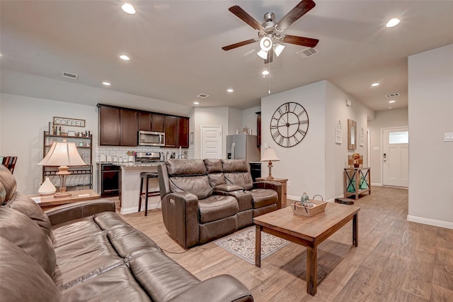 living room featuring light wood finished floors, a ceiling fan, visible vents, and recessed lighting