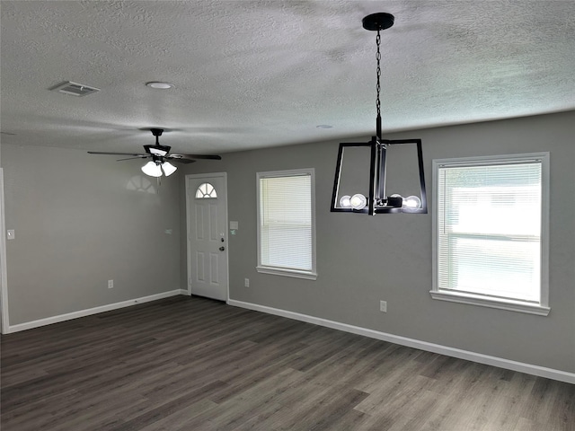 unfurnished dining area featuring baseboards, dark wood-style floors, and a textured ceiling
