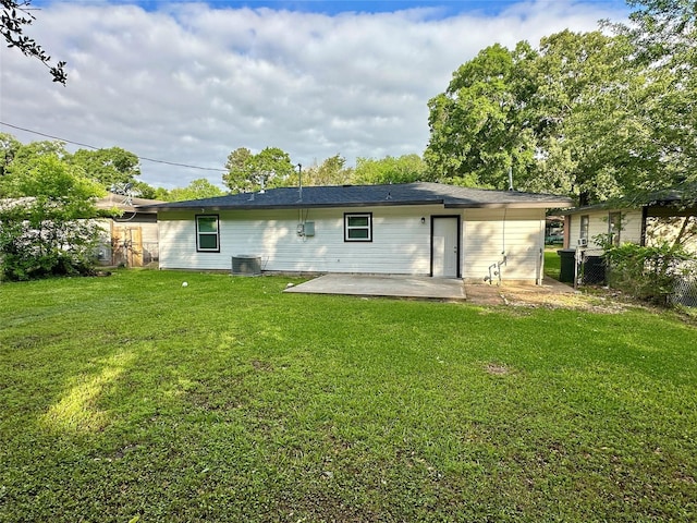 rear view of property featuring fence, a patio area, a lawn, and central AC