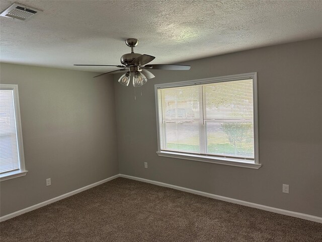 carpeted empty room featuring a textured ceiling, visible vents, baseboards, and ceiling fan