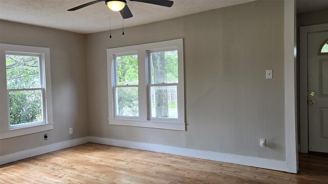 unfurnished room featuring baseboards, a ceiling fan, wood finished floors, and a textured ceiling