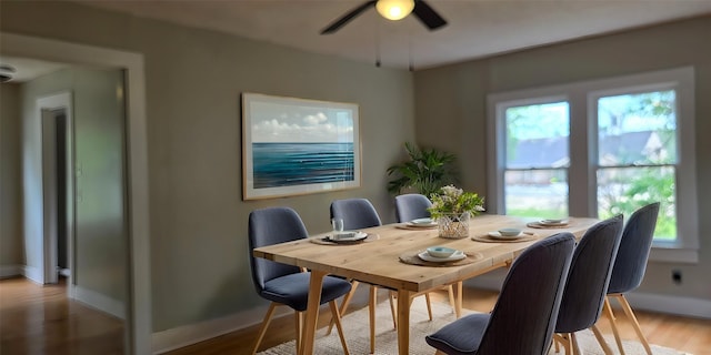 dining area featuring wood finished floors, a ceiling fan, and baseboards