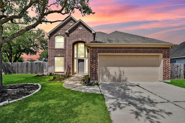 view of front of property with driveway, fence, brick siding, an attached garage, and a front yard
