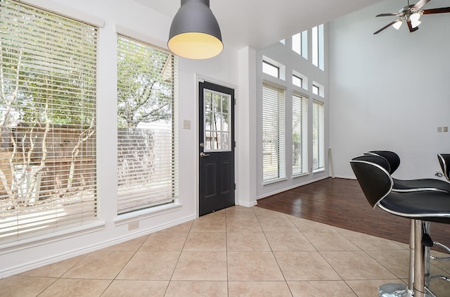 entryway with baseboards, tile patterned flooring, ceiling fan, and a healthy amount of sunlight