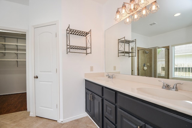 bathroom with tile patterned flooring, a sink, double vanity, and a stall shower