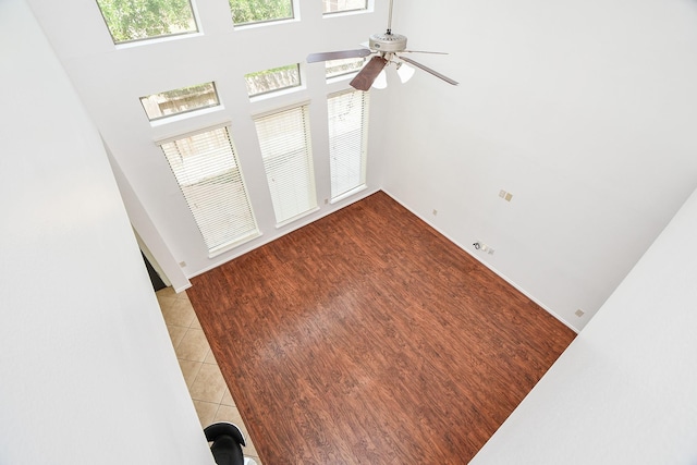 spare room with a ceiling fan, a towering ceiling, and light tile patterned flooring