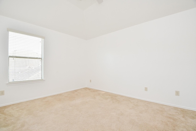 spare room featuring light carpet, a ceiling fan, and baseboards