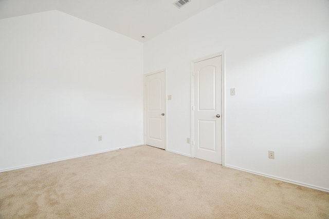 empty room with lofted ceiling, light carpet, baseboards, and visible vents