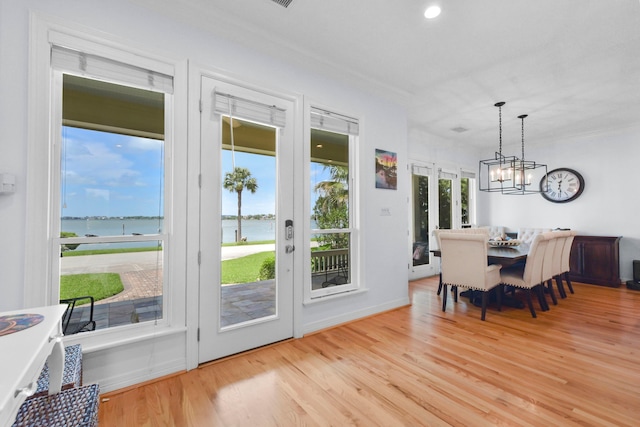 doorway to outside featuring french doors, a chandelier, a water view, and light wood-type flooring