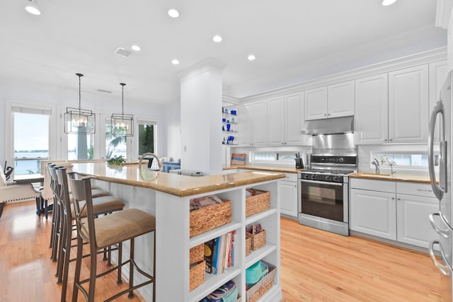 kitchen with open shelves, under cabinet range hood, a kitchen breakfast bar, and gas stove