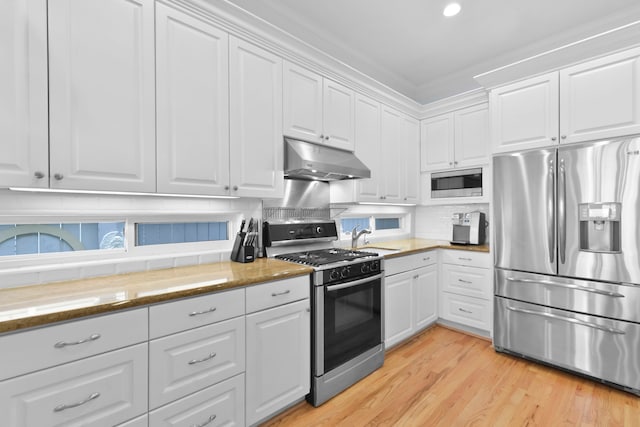 kitchen featuring stainless steel appliances, light wood-style flooring, white cabinets, backsplash, and under cabinet range hood