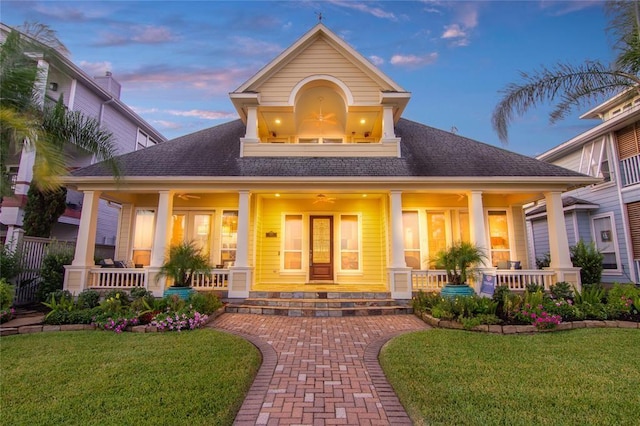 view of front of home featuring a front lawn, a shingled roof, and covered porch