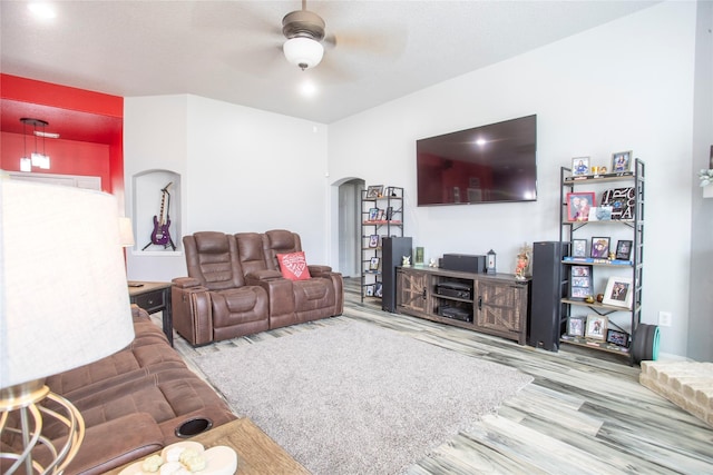 living room with arched walkways, wood finished floors, and ceiling fan