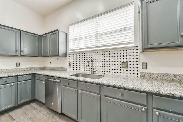 kitchen featuring stainless steel dishwasher, gray cabinetry, a sink, and plenty of natural light