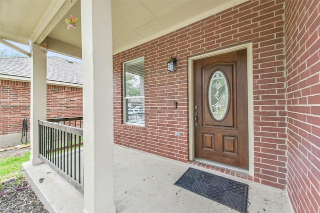 property entrance with brick siding and a porch
