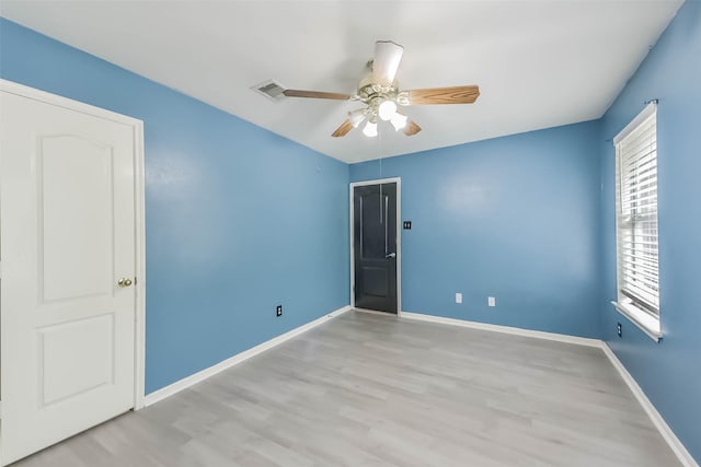 empty room featuring a ceiling fan, light wood-style floors, and visible vents