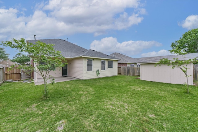 back of property with a shingled roof, a fenced backyard, a yard, and a patio