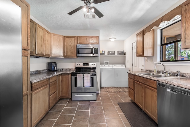 kitchen with a ceiling fan, a sink, a textured ceiling, washing machine and dryer, and appliances with stainless steel finishes