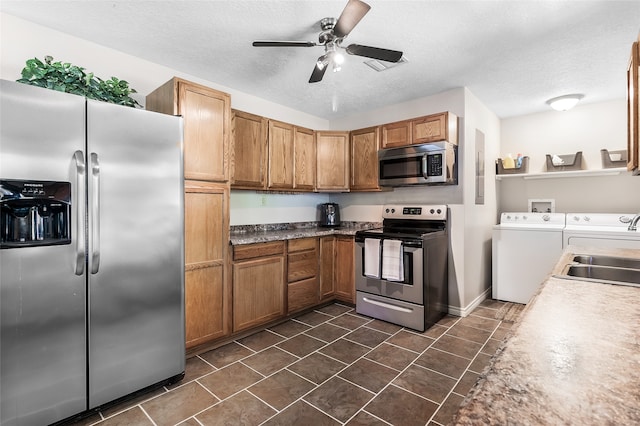 kitchen featuring a ceiling fan, a sink, washing machine and dryer, a textured ceiling, and appliances with stainless steel finishes