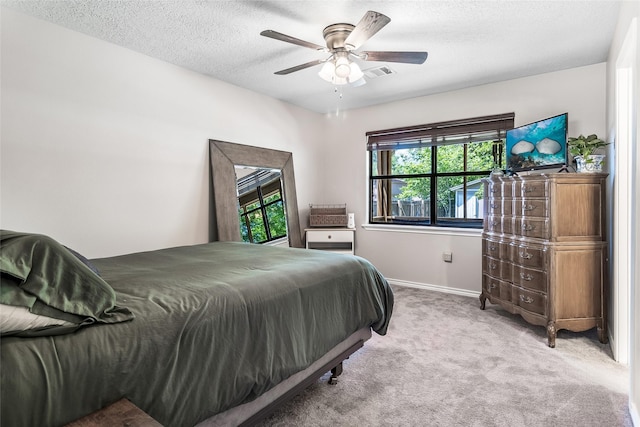 bedroom featuring visible vents, a ceiling fan, baseboards, a textured ceiling, and light colored carpet