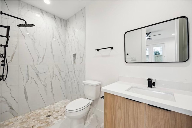 bathroom with vanity, ceiling fan, toilet, marble finish floor, and a marble finish shower