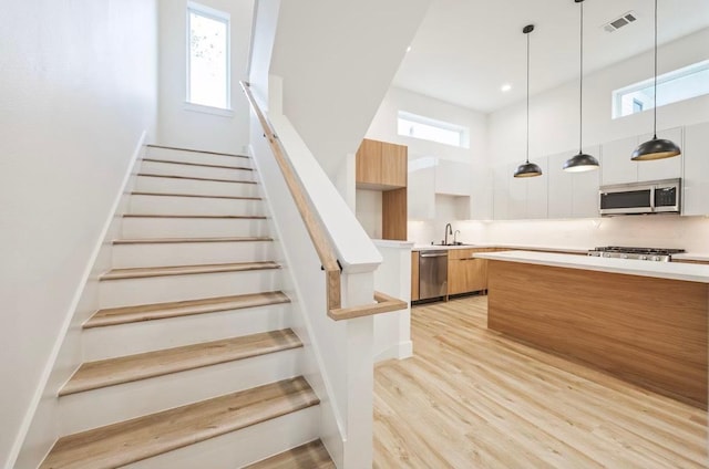 staircase featuring visible vents, a wealth of natural light, wood finished floors, and baseboards