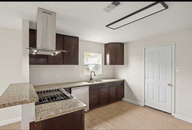 kitchen featuring island exhaust hood, a sink, dark brown cabinetry, and baseboards