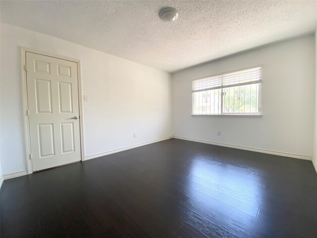 1823 Mandrill Ln, Houston, TX 77067 - spare room featuring baseboards, dark wood finished floors, and a textured ceiling