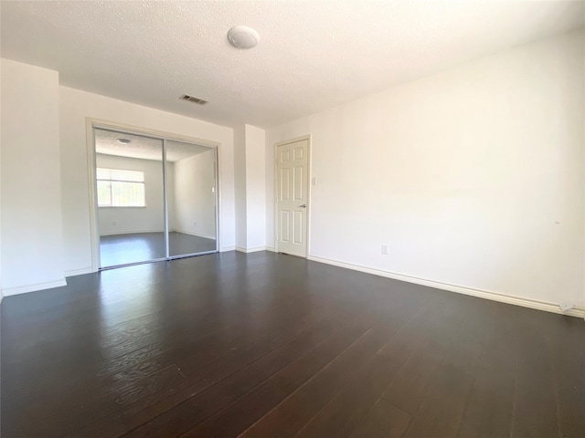 1823 Mandrill Ln, Houston, TX 77067 - empty room featuring baseboards, dark wood-style flooring, a textured ceiling, and visible vents