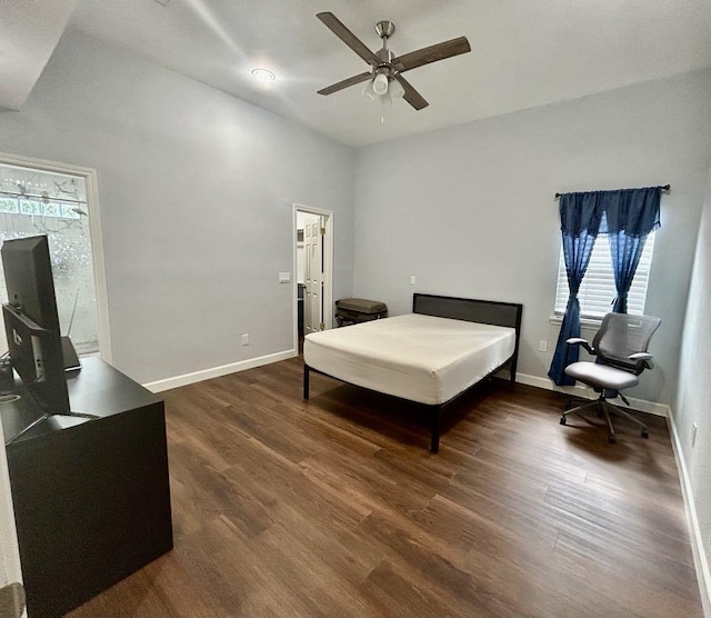bedroom with a ceiling fan, baseboards, dark wood-type flooring, and multiple windows