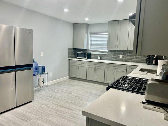 11115 Oakcenter Dr, Houston, TX 77072 - kitchen featuring stainless steel appliances, decorative backsplash, gray cabinetry, baseboards, and recessed lighting
