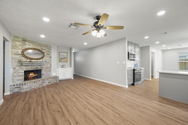 unfurnished living room featuring light wood-type flooring, visible vents, and a textured ceiling