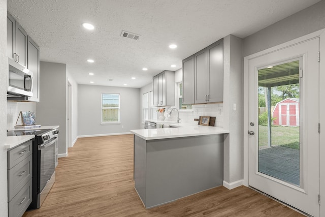 kitchen featuring stainless steel appliances, light countertops, visible vents, baseboards, and gray cabinetry