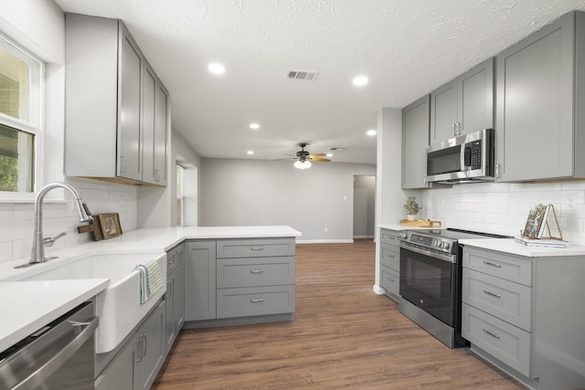kitchen with appliances with stainless steel finishes, gray cabinetry, visible vents, and recessed lighting